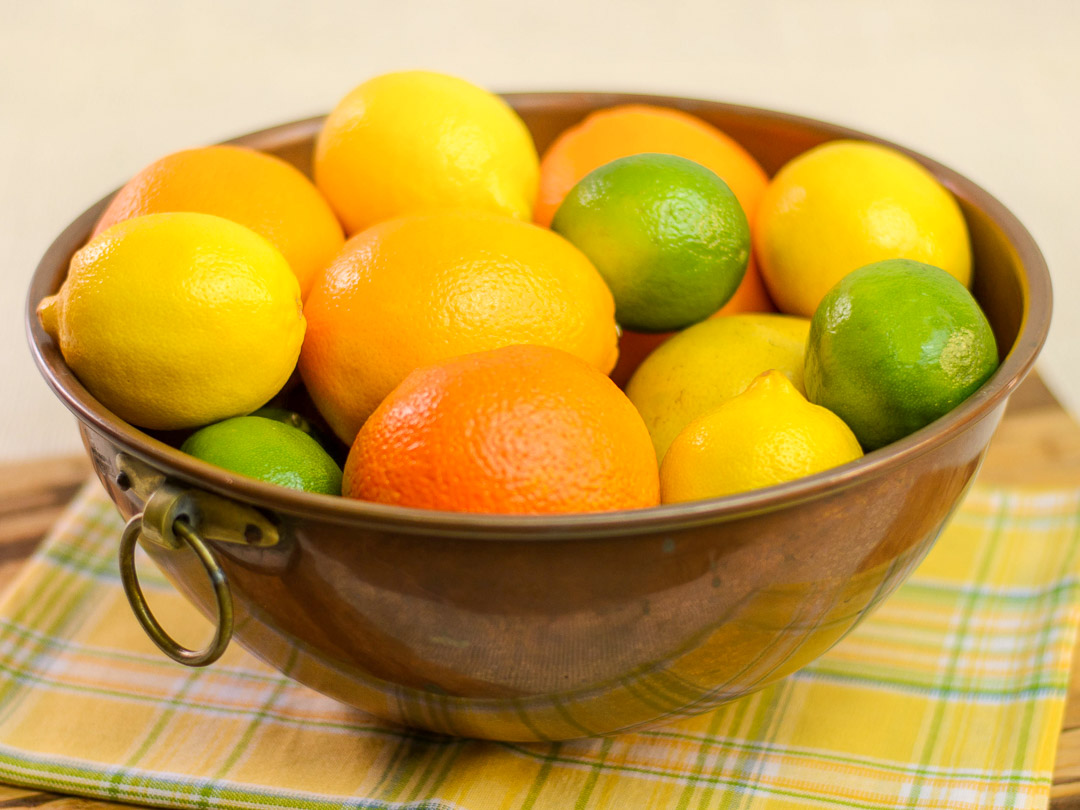 Brass bowl filled with citrus fruits.