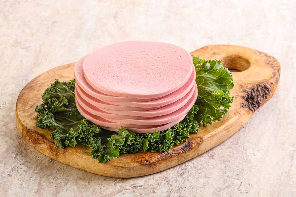 bologna slices and lettuce on a cutting board.