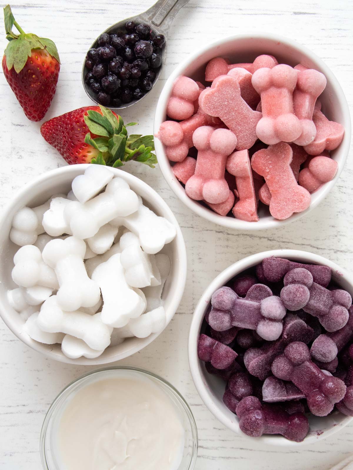 bowls of coconut, strawberry, and blueberry frozen dog treats.