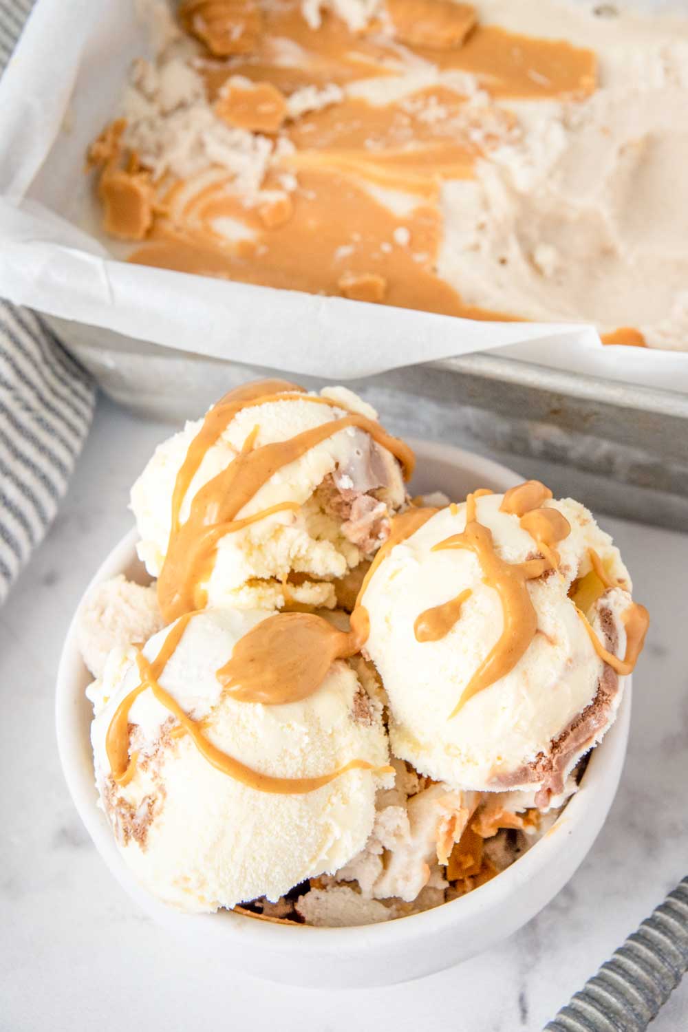 Homemade banana peanut butter ice cream in a loaf pan and scoops in a bowl.
