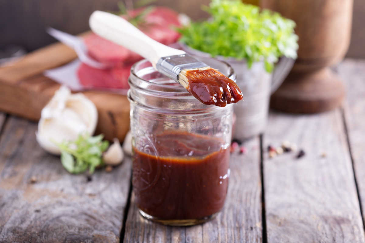 bbq sauce in a mason jar and a basting brush on top.