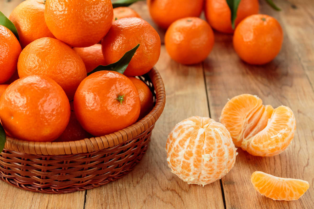 clementines in a basket and peeled ones beside it.