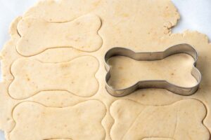 cutting gluten free dog treats dough with a bone-shaped cutter.