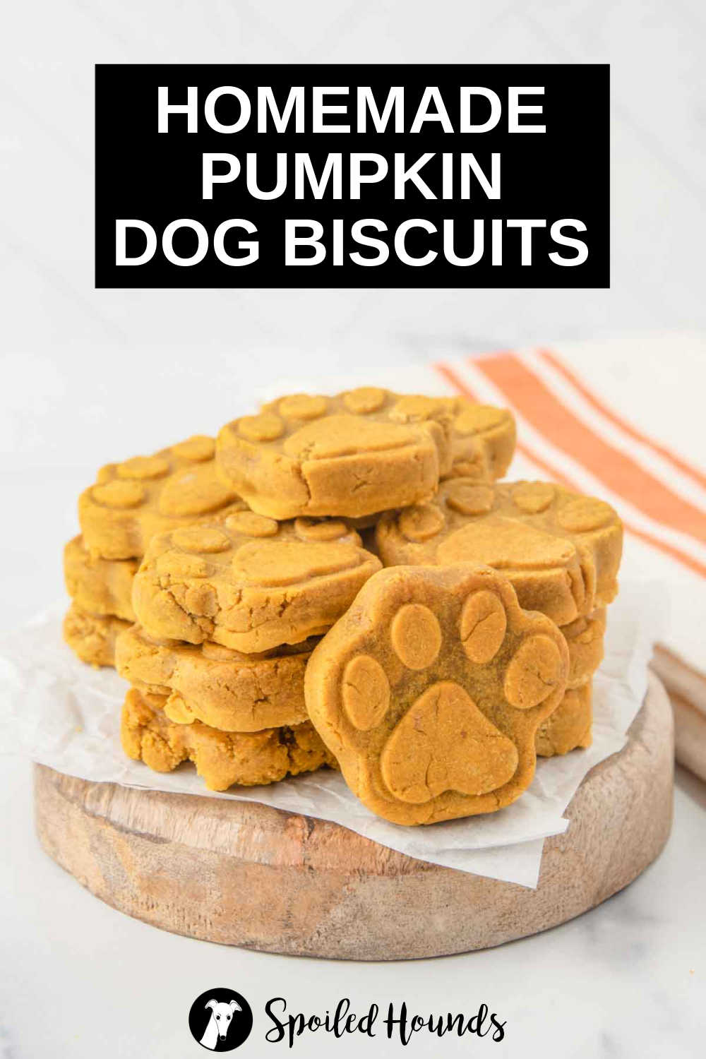 a stack of homemade pumpkin dog biscuits on a round wood board.