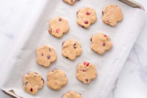 cranberry dog treats dough cutouts on a baking sheet lined with parchment paper.