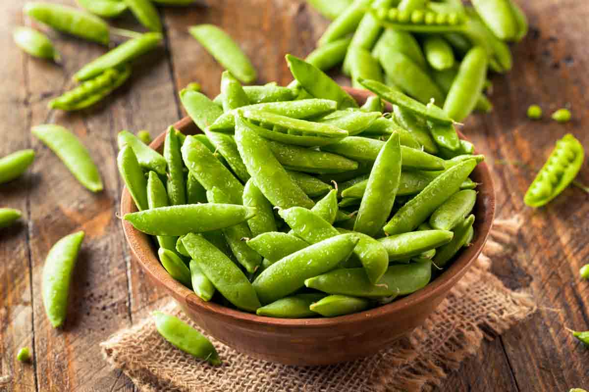 sugar snap peas in a wood bowl.