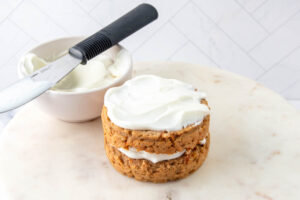 Spreading yogurt on top of a dog carrot cake layer.