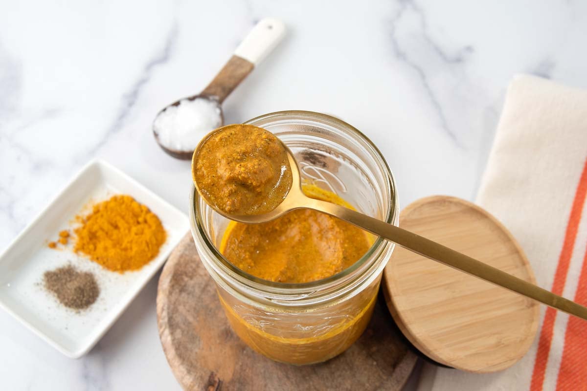 Homemade turmeric golden paste for dogs and ingredients on a marble surface.