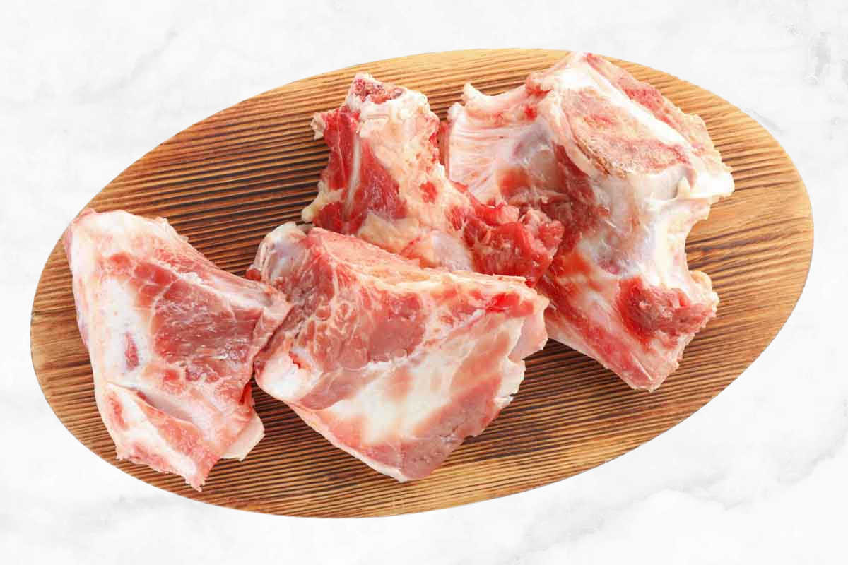 raw lamb bones on a wood platter.