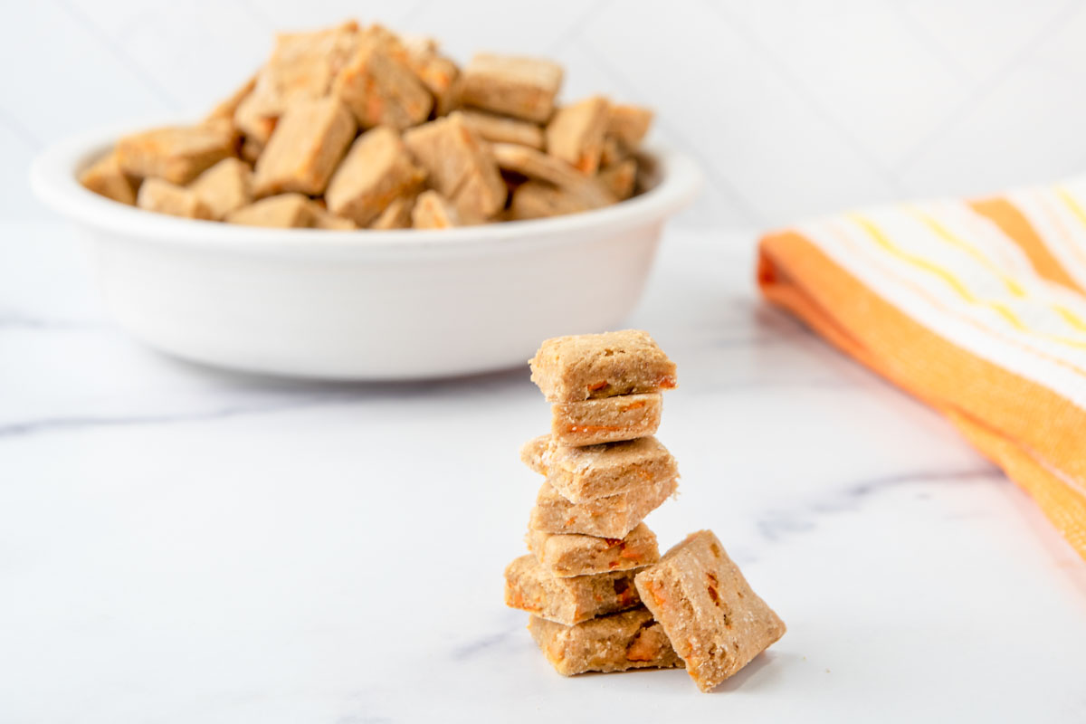 A stack of homemade low calorie dog treats in front of a bowl of them.