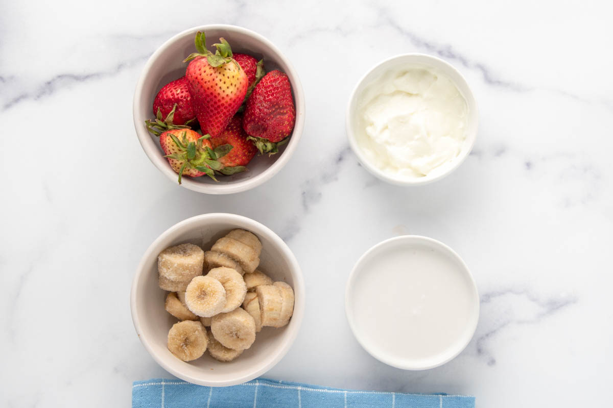 Strawberry banana dog ice cream ingredients in bowls.