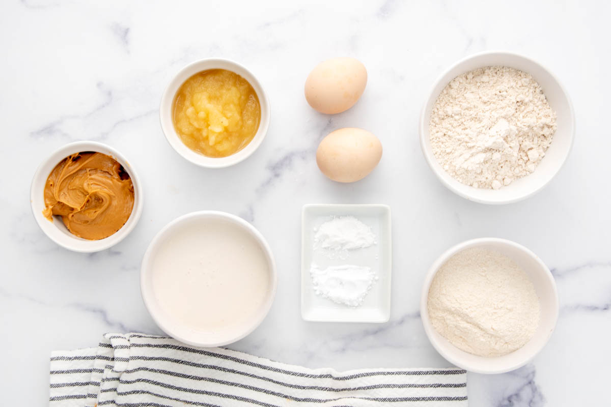 Ingredients for peanut butter cupcakes for dogs on a marble surface.