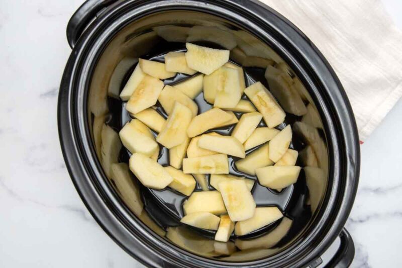 Sliced apples and water in a crockpot slow cooker.