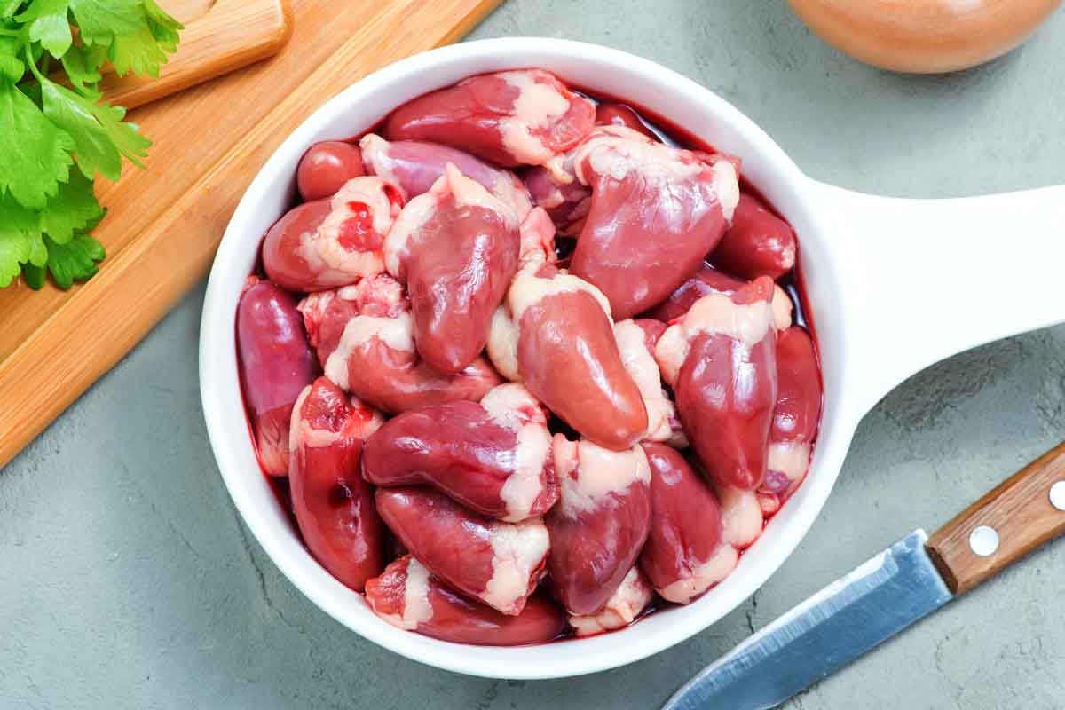 Overhead view of raw chicken hearts in a bowl.