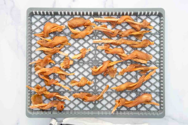 Chicken wrapped sweet potato dog treats on a dehydrator rack after dehydrating.