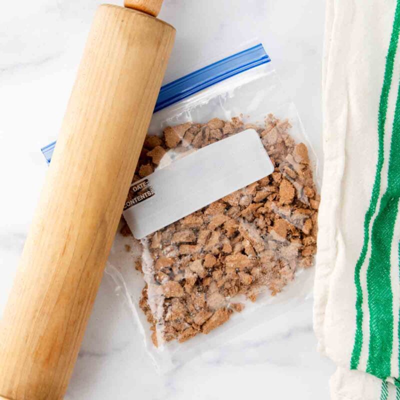 Crushed dog biscuits in a plastic bag and a rolling pin.