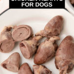 Whole and sliced cooked chicken hearts for dogs on a plate.