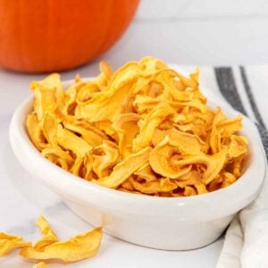 Homemade dehydrated pumpkin for dogs in a bowl.