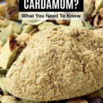 A spoon of ground cardamom powder on top of cardamom seeds.