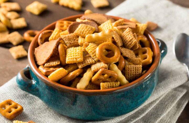 Chex mix in a bowl on top of a cloth napkin.