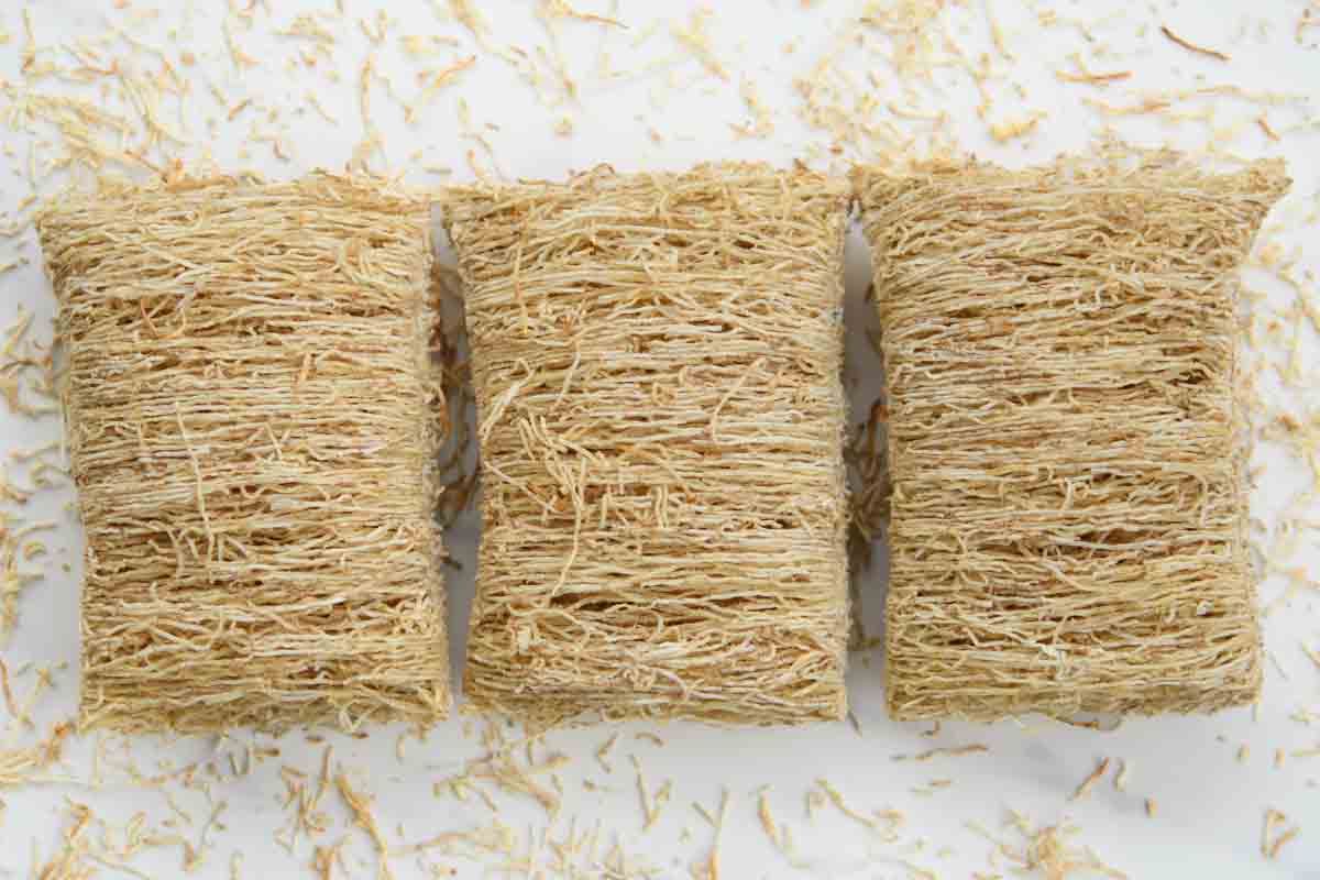 Three pieces of shredded wheat big biscuit cereal.