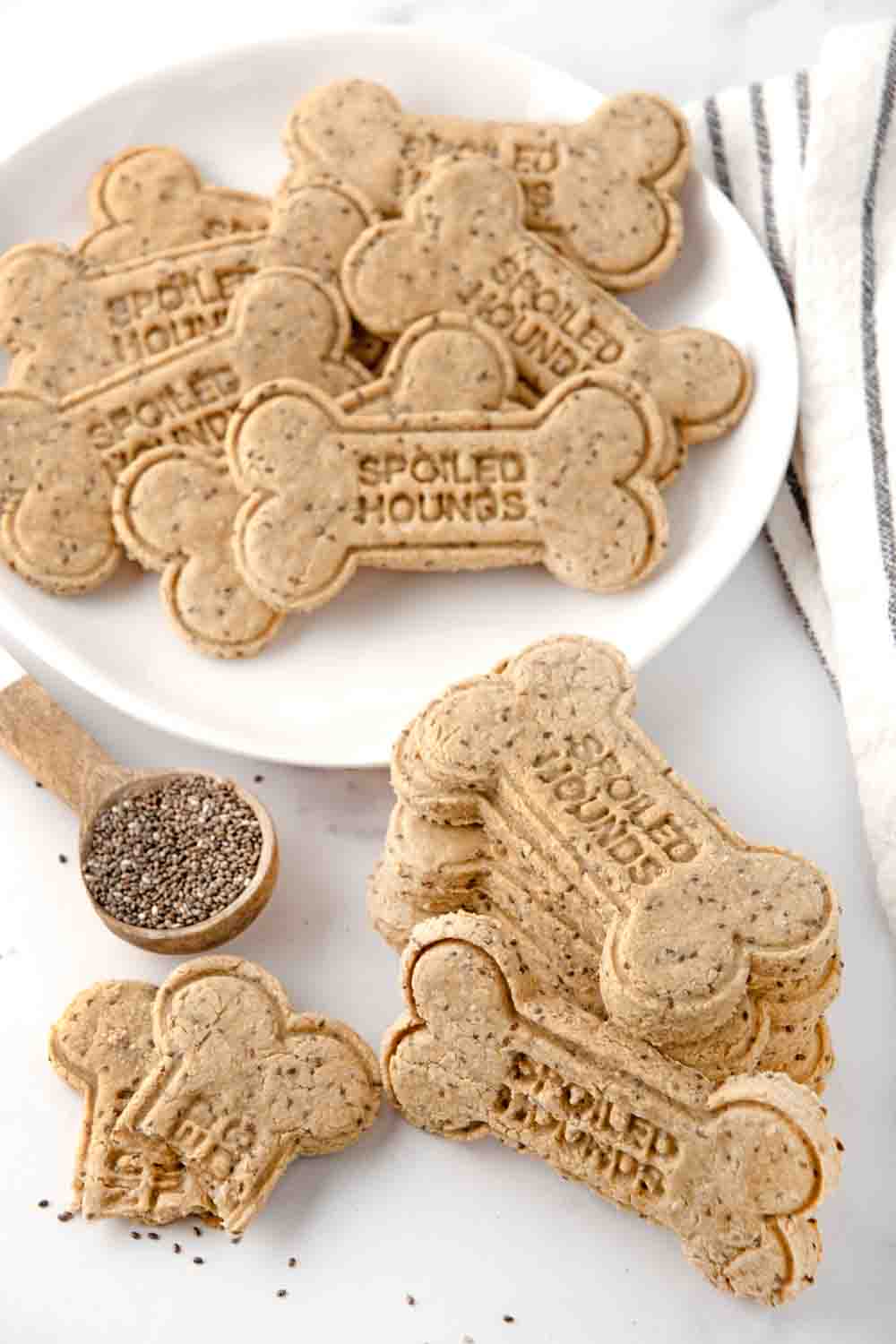 Homemade chia seed dog treats in a stack and on a plate and chia seeds in a spoon.