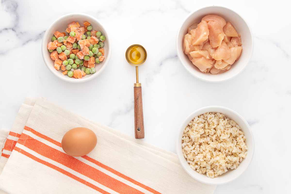 Fried rice for dogs ingredients on a marble surface.