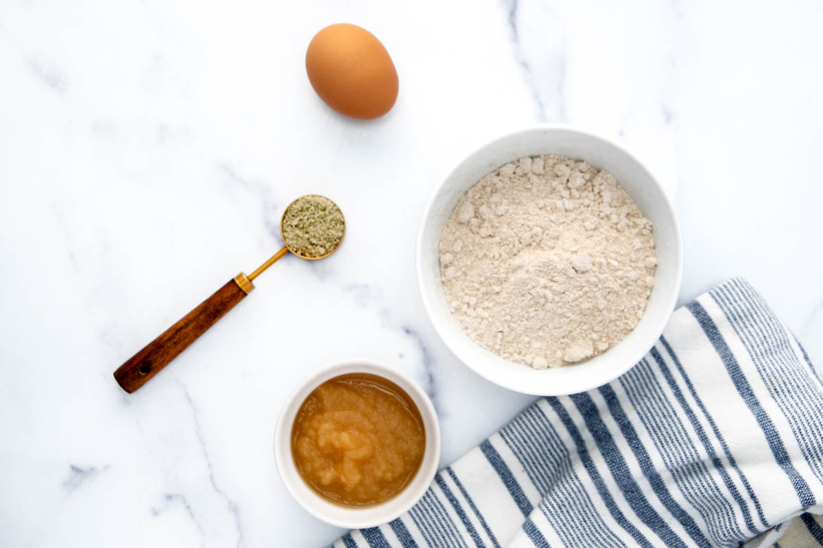 Homemade pumpkin seed dog treats ingredients on a marble surface.