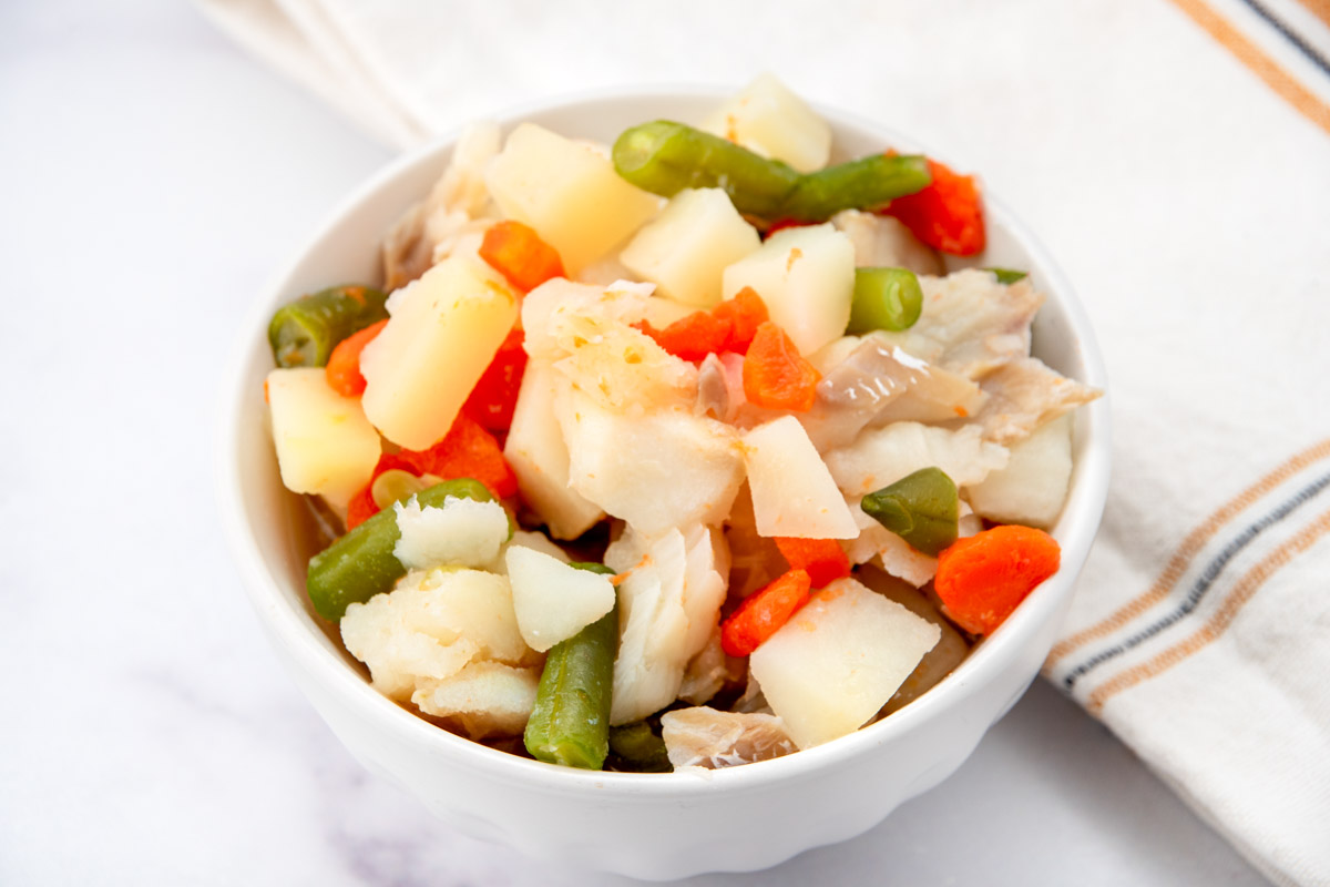 Homemade fish stew for dogs in a bowl and a kitchen towel.