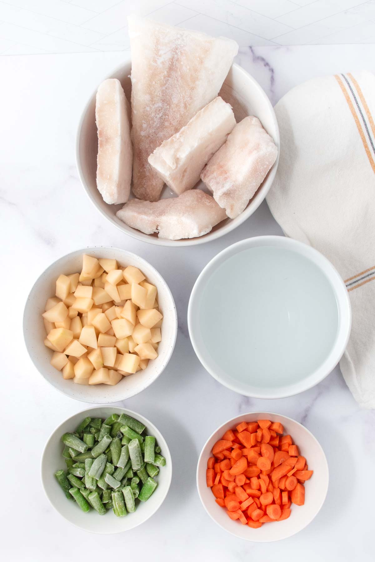 Homemade fish stew for dogs ingredients in bowls.