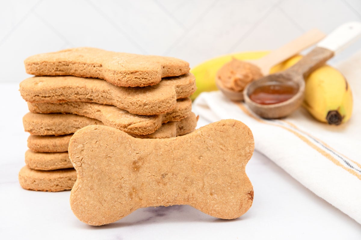 Homemade honey dog treats in a stack, honey, peanut butter, and a banana.