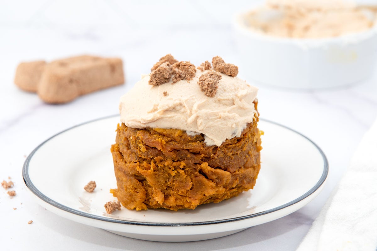 Microwave peanut butter pumpkin mug cake for dogs with frosting on a plate.