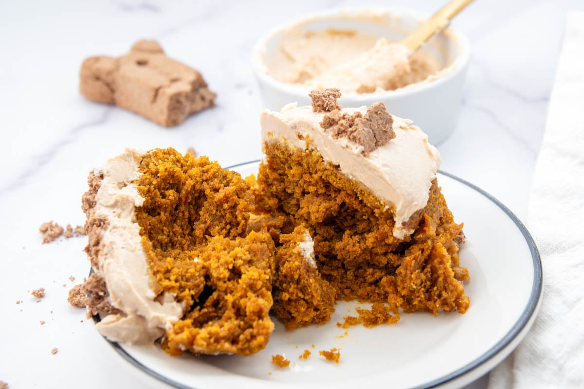 Microwave mug cake for dogs with frosting torn in half on a plate.