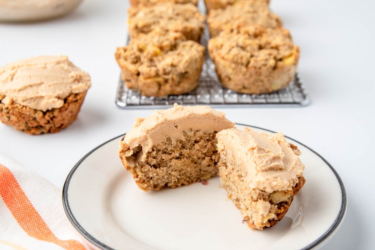Homemade unfrosted apple pupcakes on a wire rack and a frosted one on a plate.