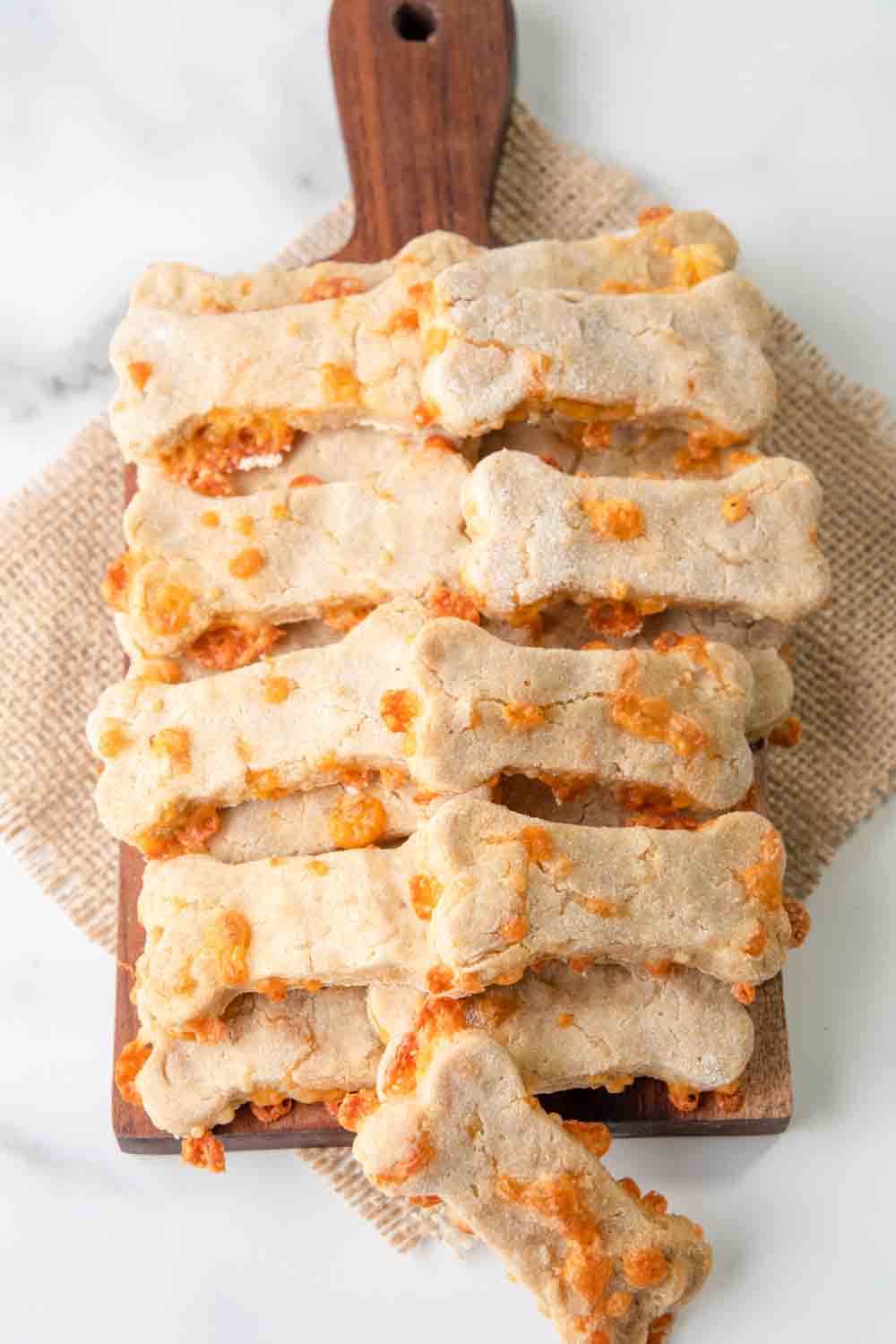 Homemade cheddar cheese dog treats piled on a wood board.