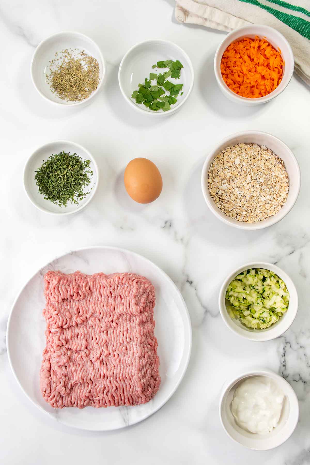 Homemade chicken meatballs for dogs ingredients on a marble surface.