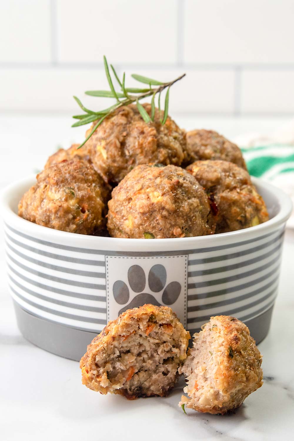 Homemade chicken meatballs for dogs in a dog bowl and one in front cut in half.