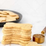 A stack of homemade anise dog treats and anise seeds in a measuring spoon.