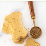 Homemade bone-shaped anise dog treats and anise seeds in a measuring spoon.