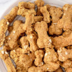 Homemade bone-shaped ground turkey dog treats piled on a plate.