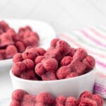 Homemade bone-shaped beet dog treats in a bowl and on a plate.