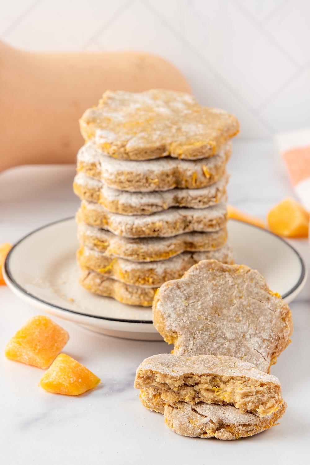 Homemade butternut squash dog treats stacked on a plate and a butternut squash behind it.