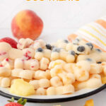 Homemade frozen peach dog treats, a peach, strawberry, pineapple, and blueberries.