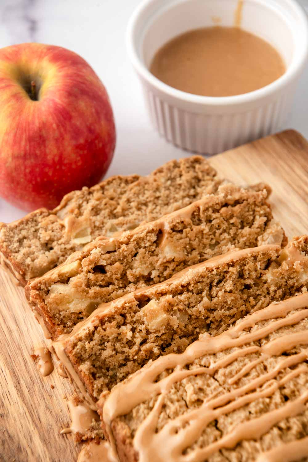 Homemade peanut butter cake for dogs, and apple, and a cup of peanut butter drizzle.
