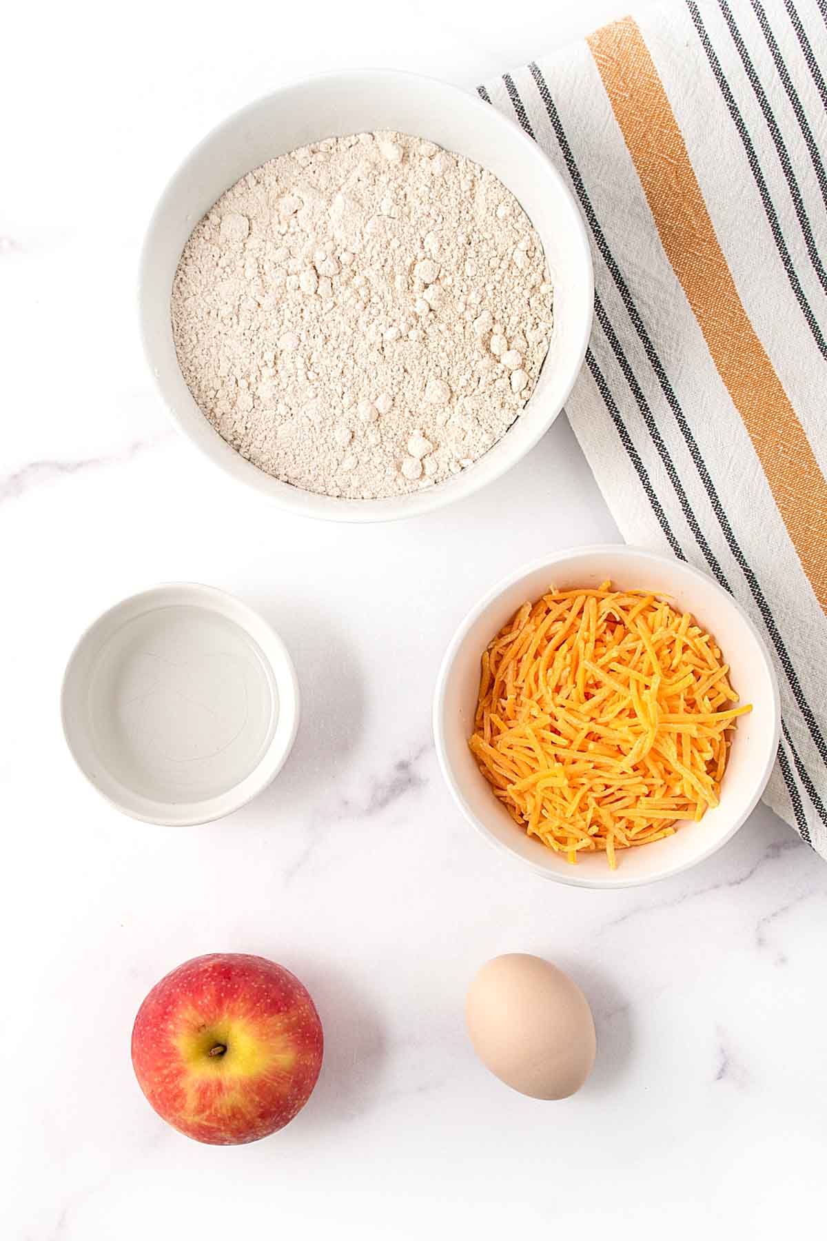Homemade apple cheddar dog treats ingredients on a marble surface.