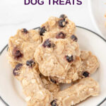 Homemade paw and bone-shaped duck and blueberry dog treats on a plate.