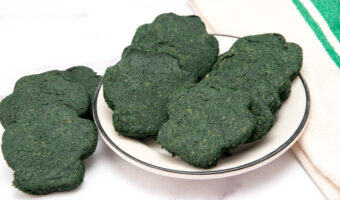 Homemade spirulina dog treats on a beside a small plate.