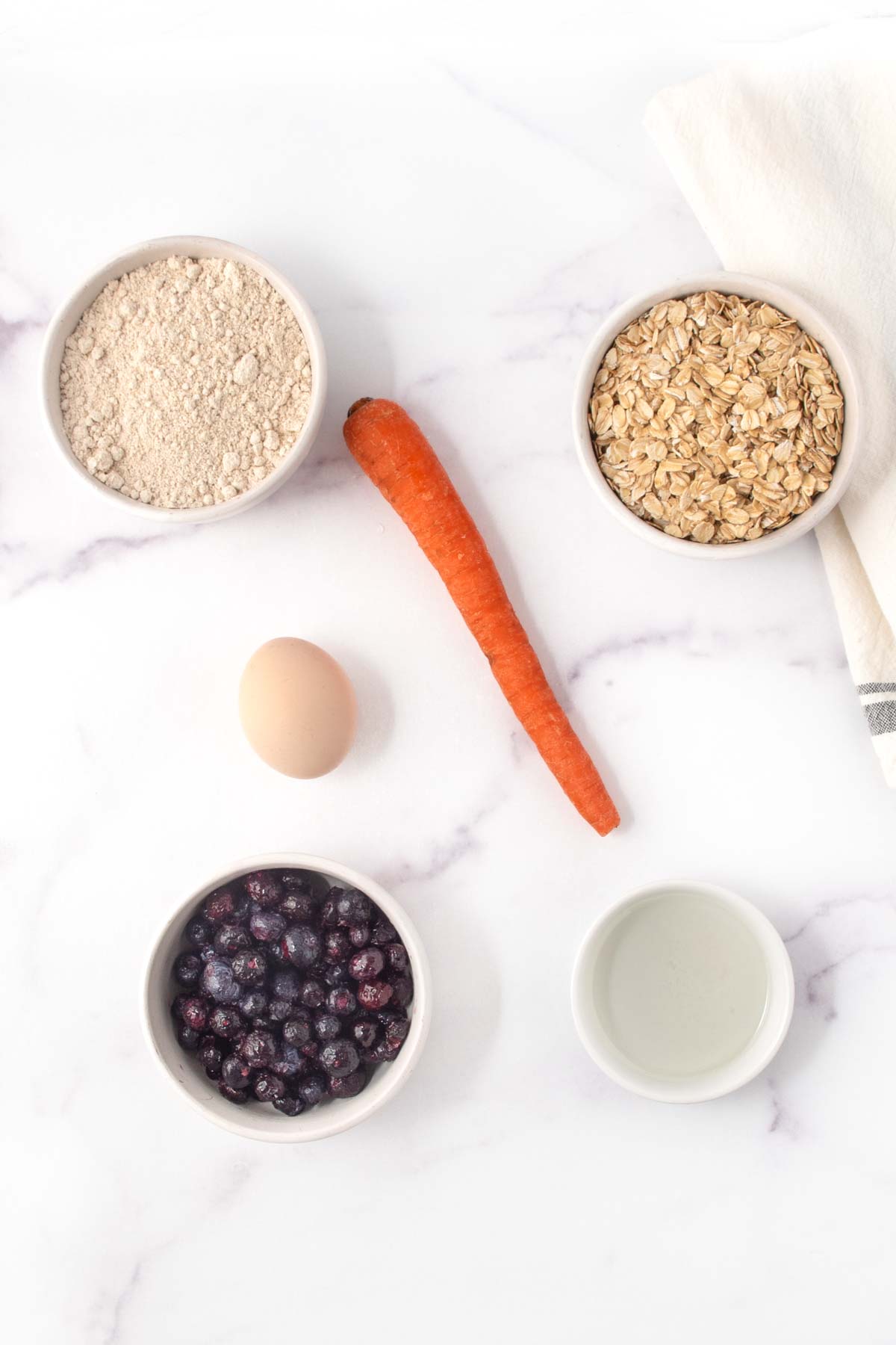 Homemade blueberry carrot dog treats ingredients on a marble surface.