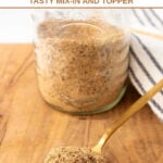Homemade dog food seasoning in a glass jar and a spoonful in front of it.