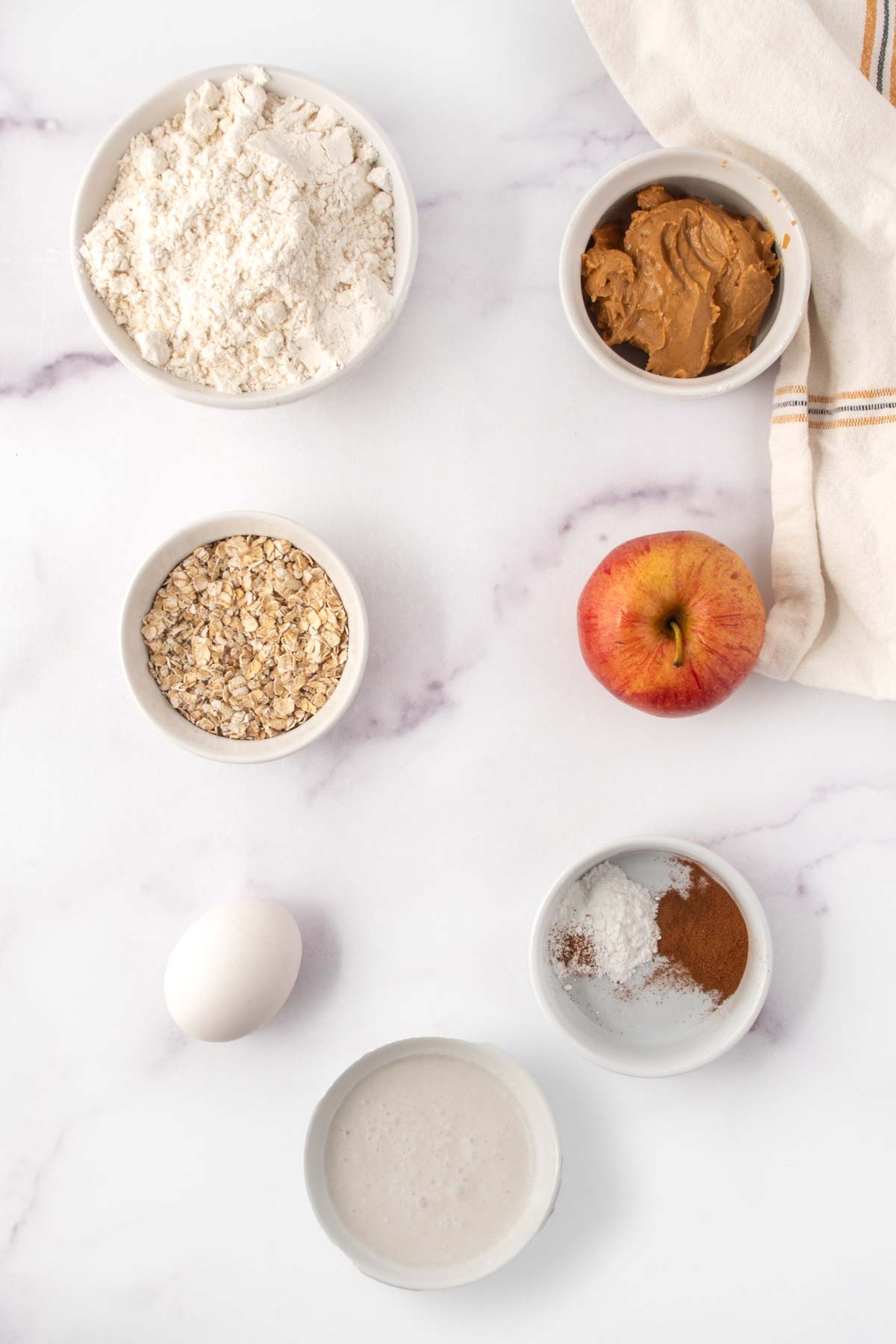 Homemade apple muffins for dogs ingredients on a marble surface.